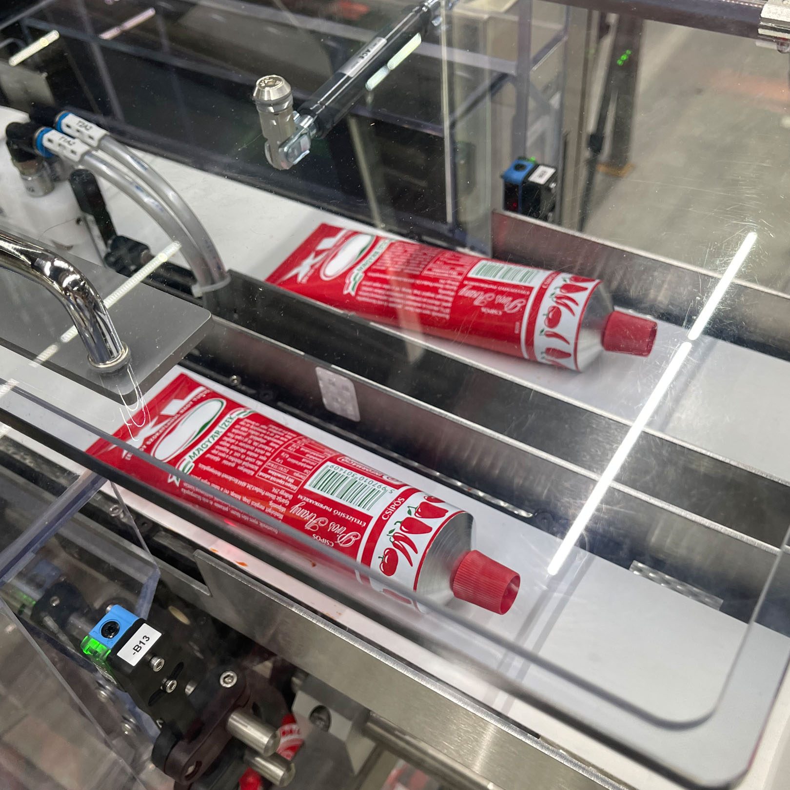 Rote Tuben in einer hygienisch konstruierten Abfüllanlage aus Edelstahl.