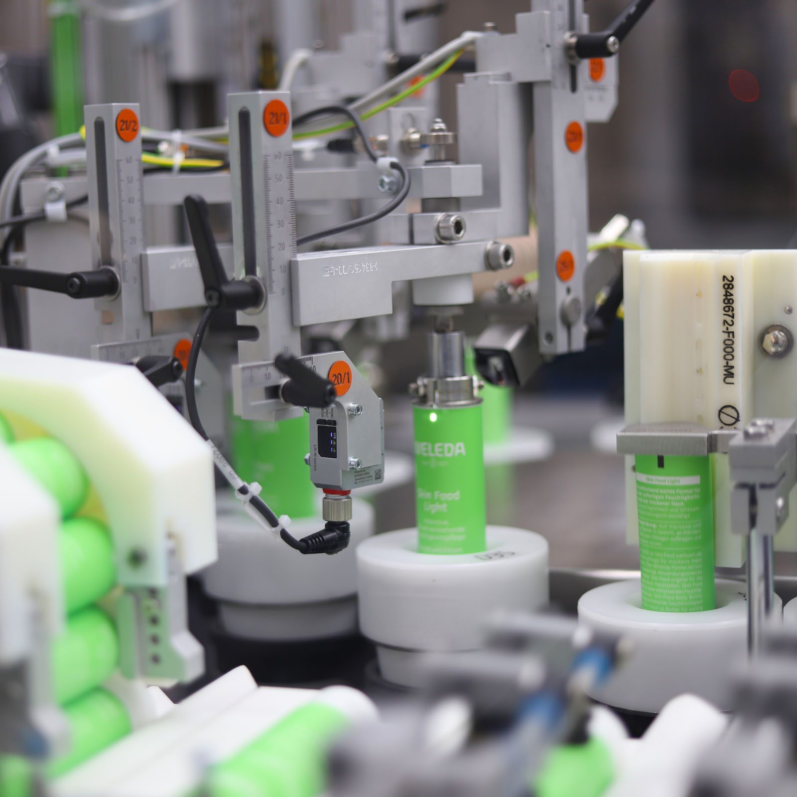 Weleda Tuben in einer automatisierten Verpackungsanlage mit Sensorik und mechanischen Führungselementen.