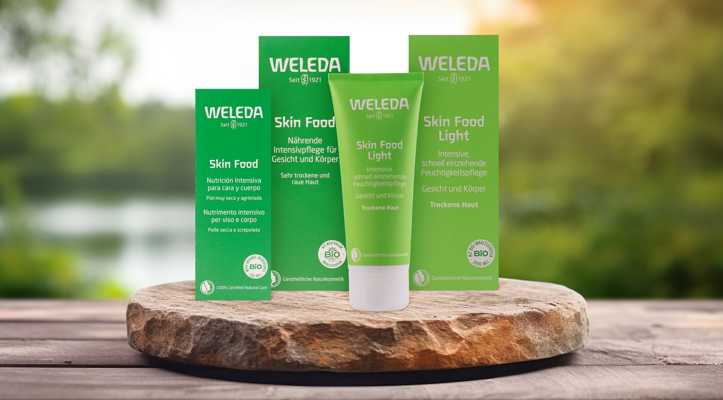 Weleda‑Skin‑Food‑Produkte vor einem unscharfen Naturhintergrund.