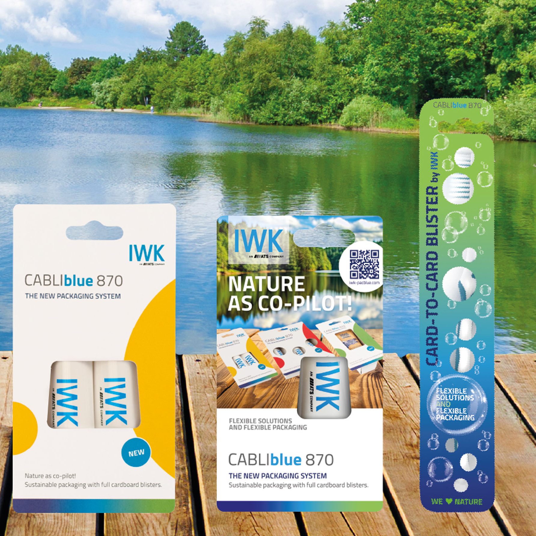 Verschiedene IWK card‑to‑card‑Verpackungen auf einem Holzsteg vor natürlichem Seehintergrund.