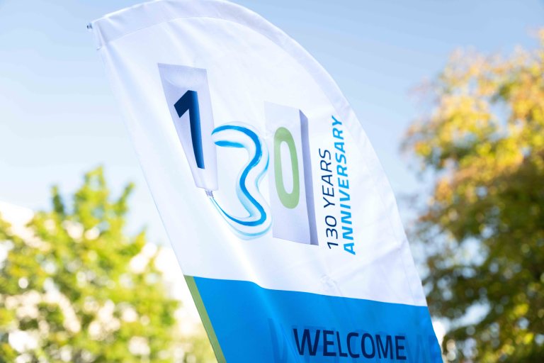 Flag with "130 Years Anniversary" print outdoors.