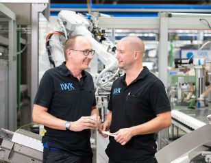 Employees in the production area exchanging information in front of components of an automated packaging line.