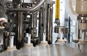 Detail of a technical assembly with stainless steel components and dosing systems in a filling machine.