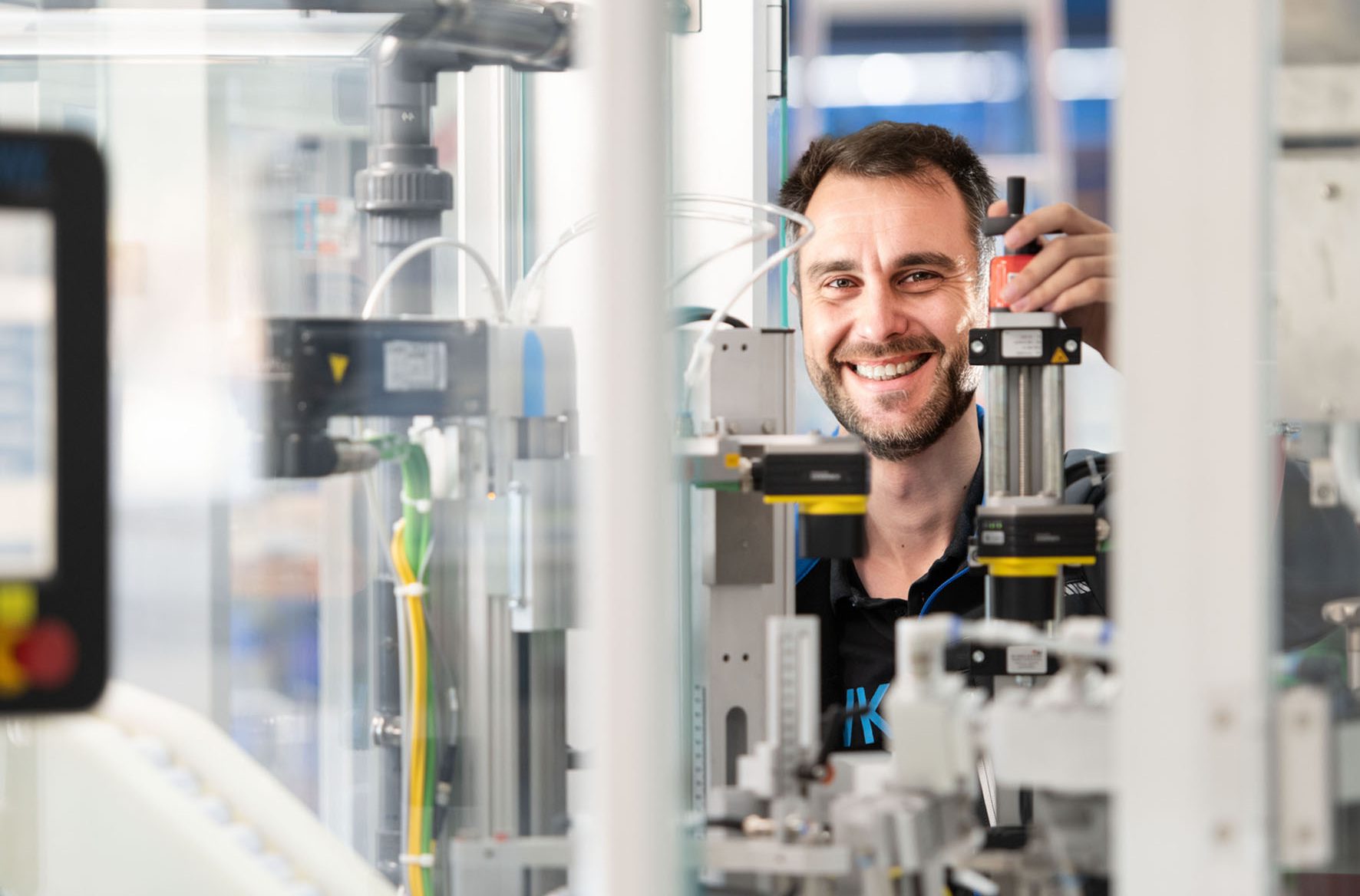 Technische Fachkraft arbeitet an Komponenten einer modernen Produktions- oder Verpackungsanlage.