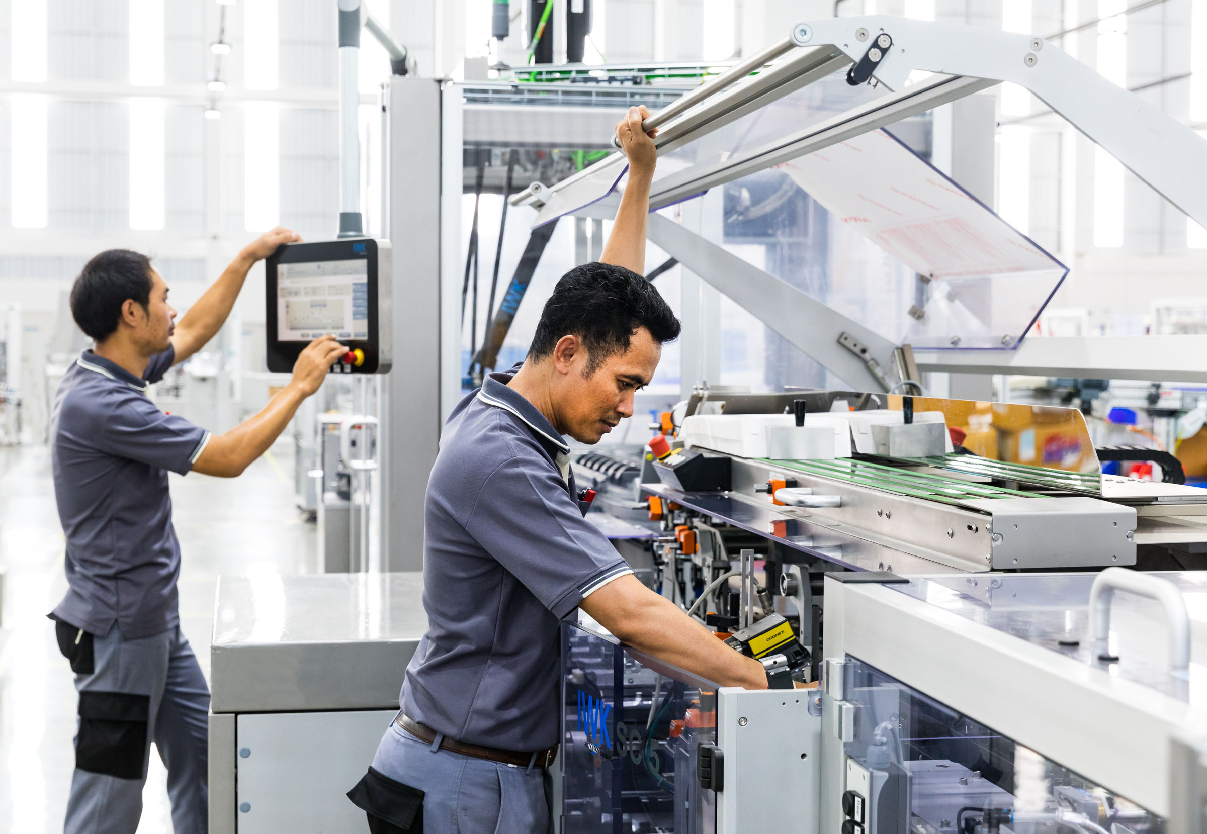 IWK Kartoniermaschine in moderner Schutzeinhausung mit Bedienstation.