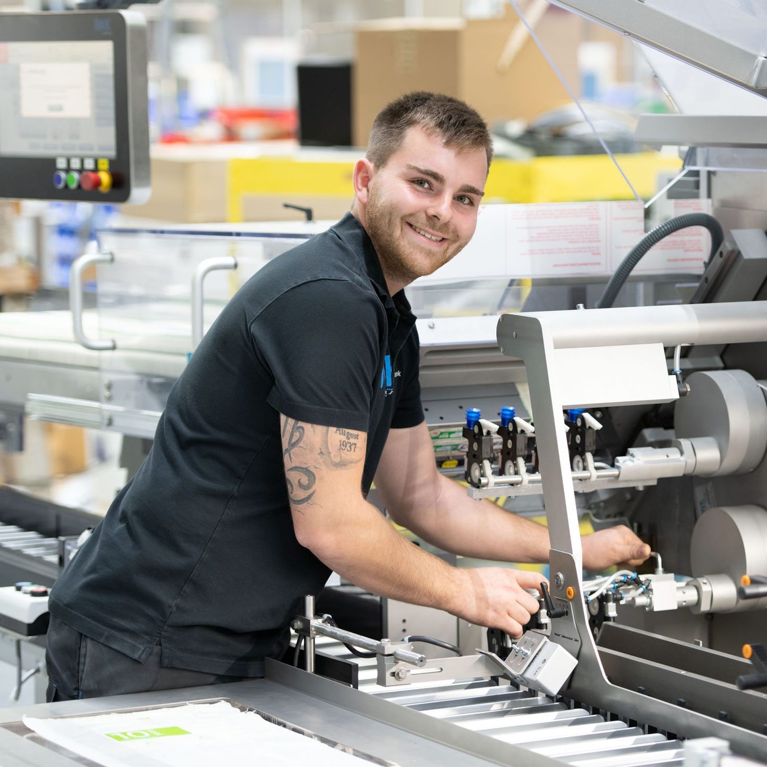 Technische Fachkraft richtet mechanische Komponenten an einem Kartonierer ein.