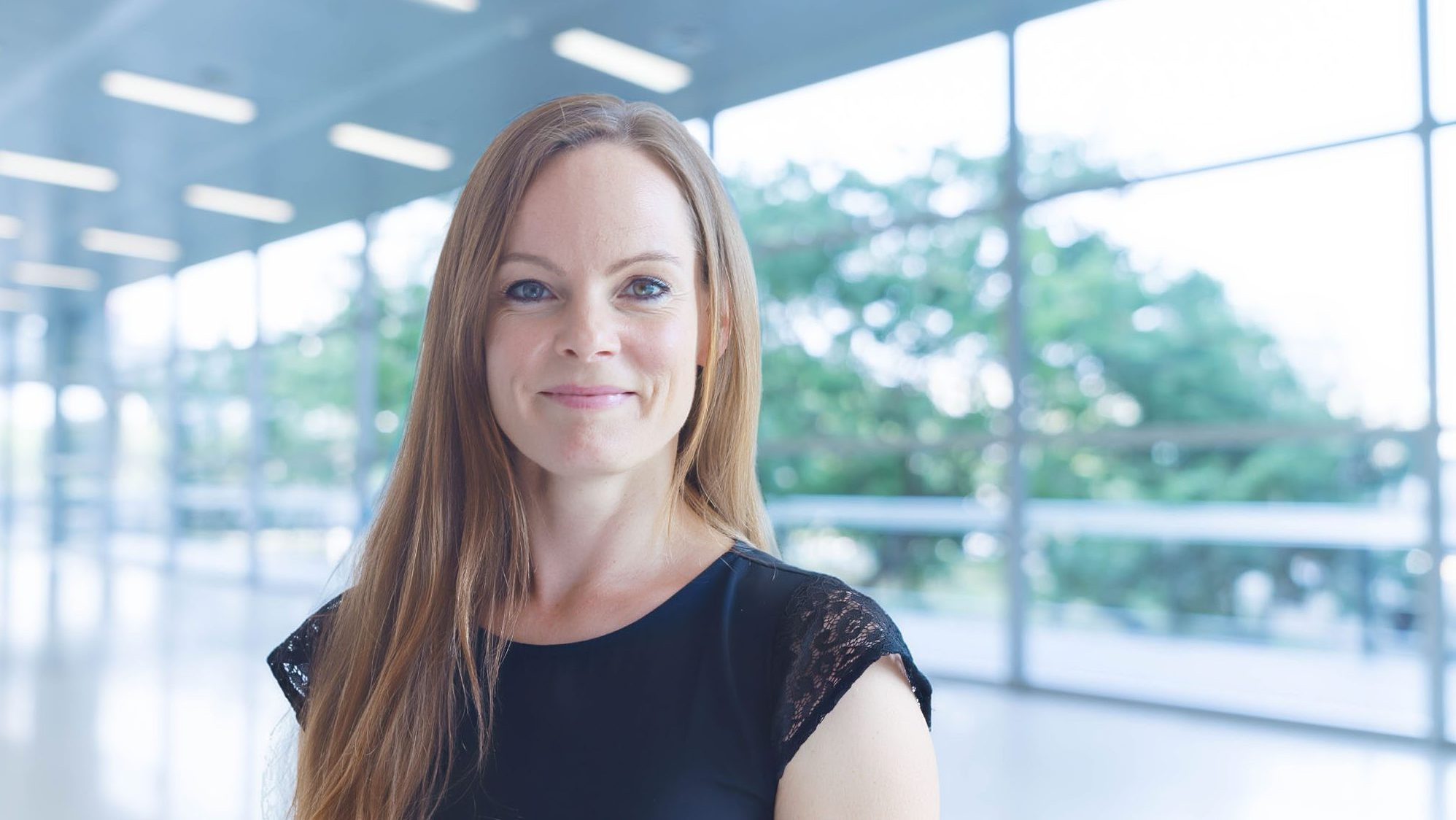 Porträt einer Person in einem modernen, lichtdurchfluteten Gebäude.