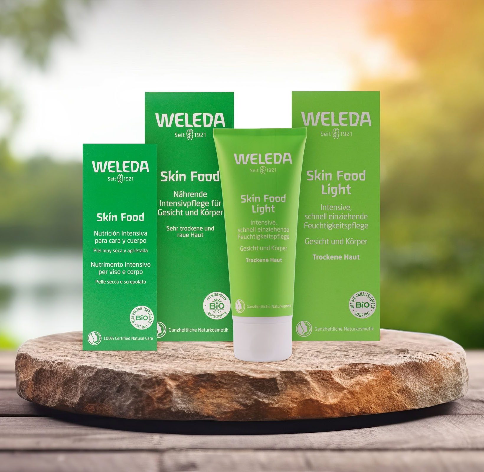 Weleda‑Skin‑Food‑Produkte vor einem unscharfen Naturhintergrund.
