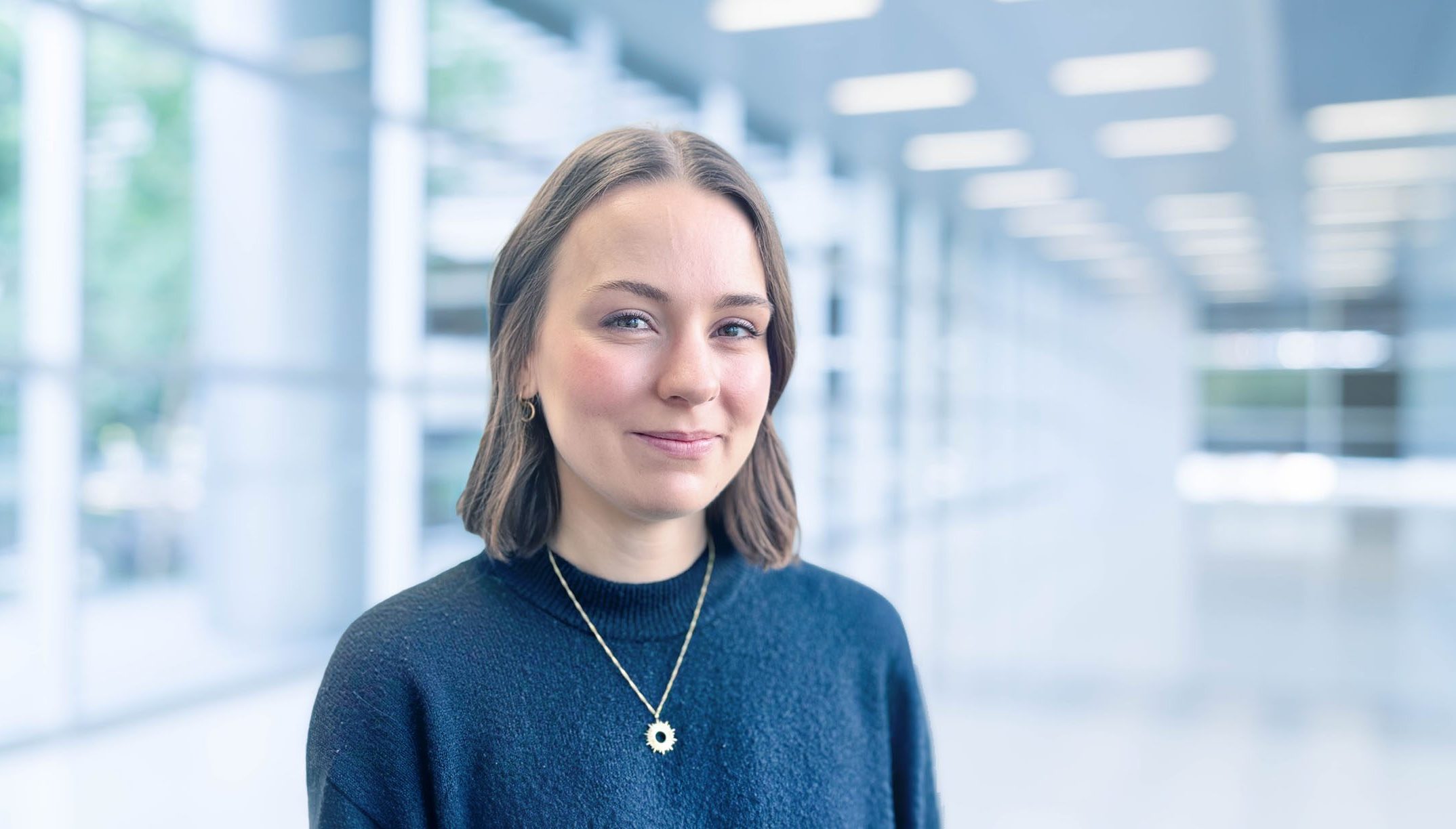 Portrait of an individual in a modern, bright architectural environment.