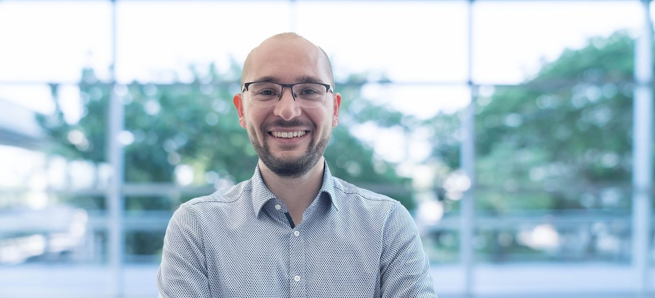 Porträt einer Person in einem modernen, lichtdurchfluteten Gebäude.