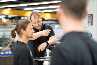Technical exchange between several people in a production environment in front of a machine plant.