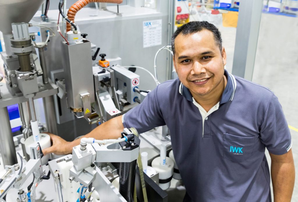 Person arbeitet an einer IWK Maschinenanlage und führt technische Einstellungen an mechanischen Modulen durch.