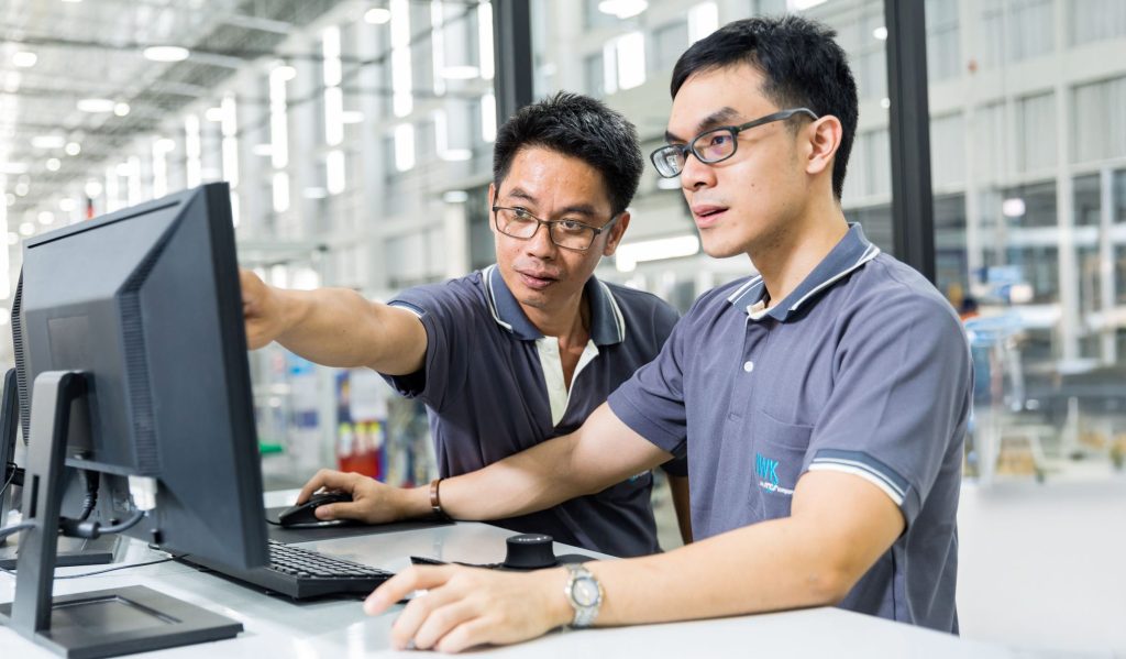 Technischer Arbeitsplatz mit zwei Personen, die gemeinsam eine Analyse an einem Computer durchführen.