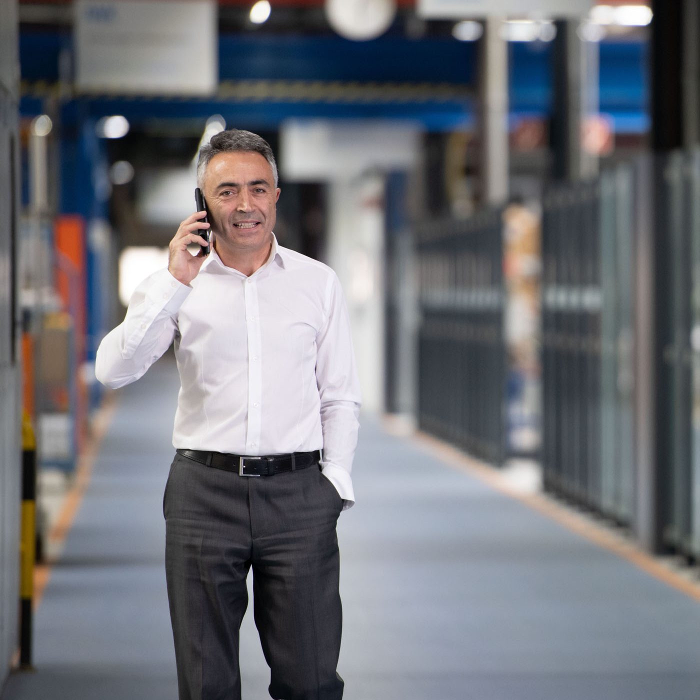 Person talking on the phone in a production hall along a machine line.