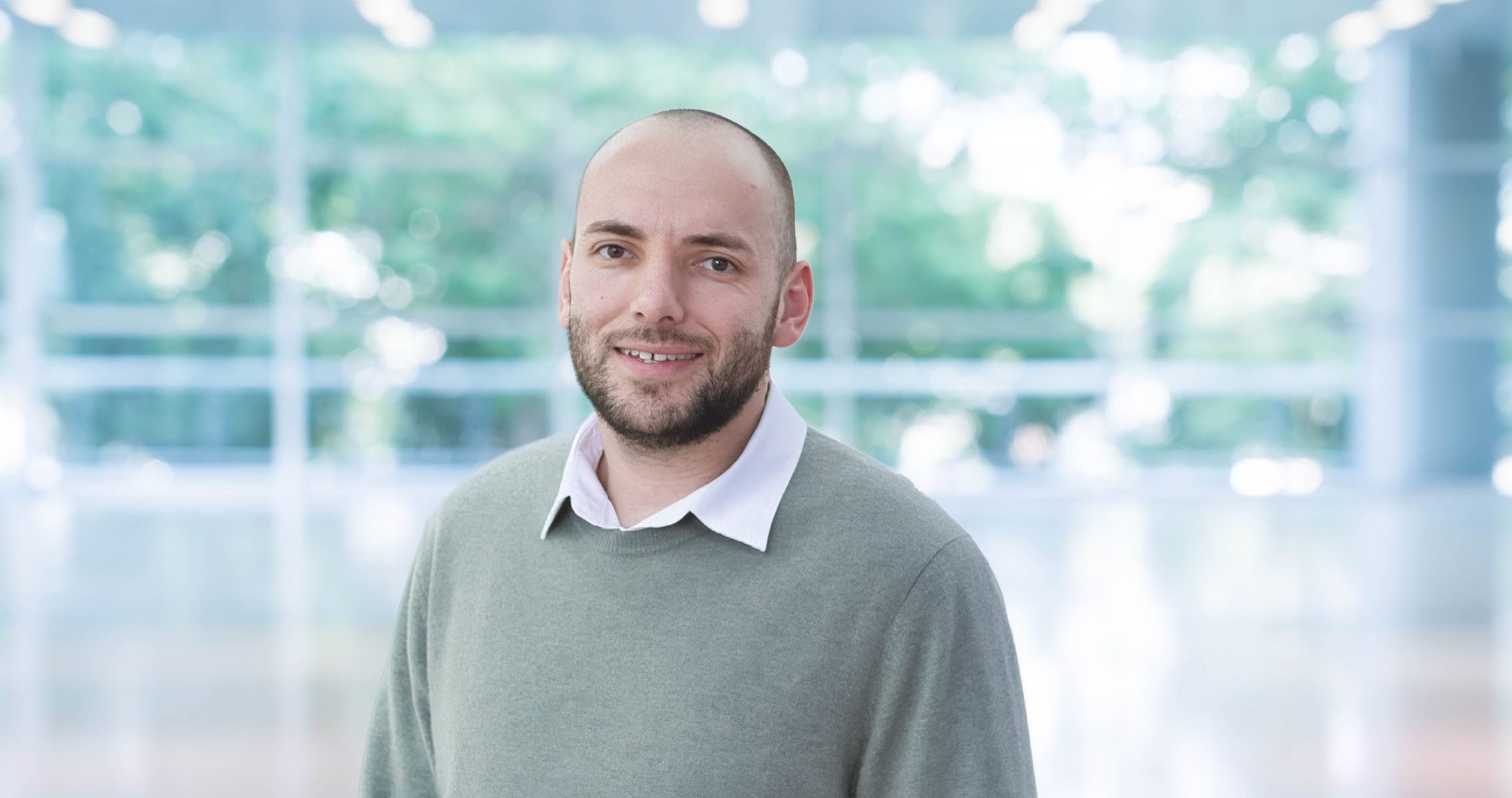 Portrait of an individual in a modern, bright architectural environment.