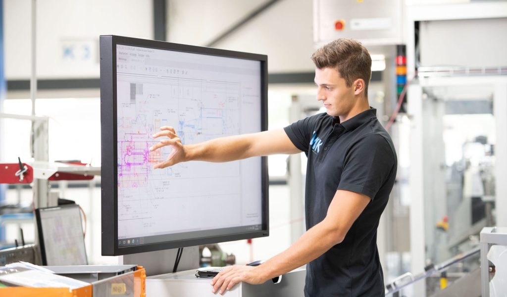 Interaktiver Großbildschirm mit technischer Konstruktionszeichnung in einer Produktionsumgebung.