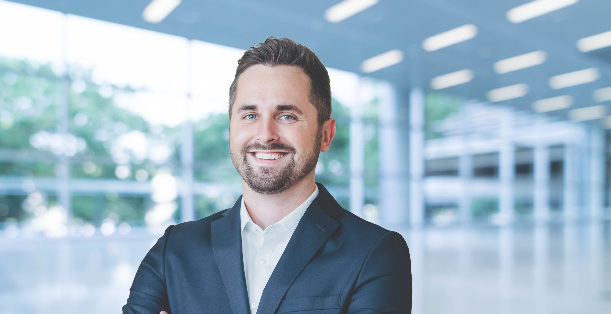 Portrait of an individual in a modern, bright architectural environment.