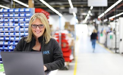 Person working with laptop in a production environment with IWK clothing.