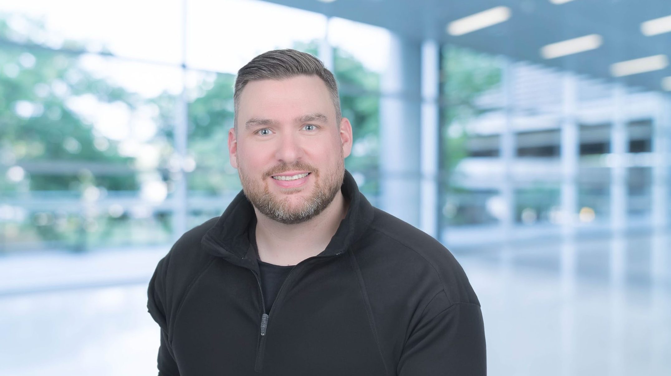 Portrait of an individual in a modern, bright architectural environment.