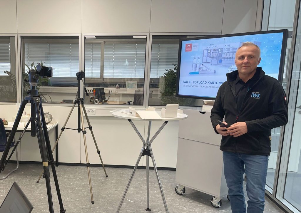 Person präsentiert technische Inhalte vor einem großen Display in einem modernen Besprechungsraum.