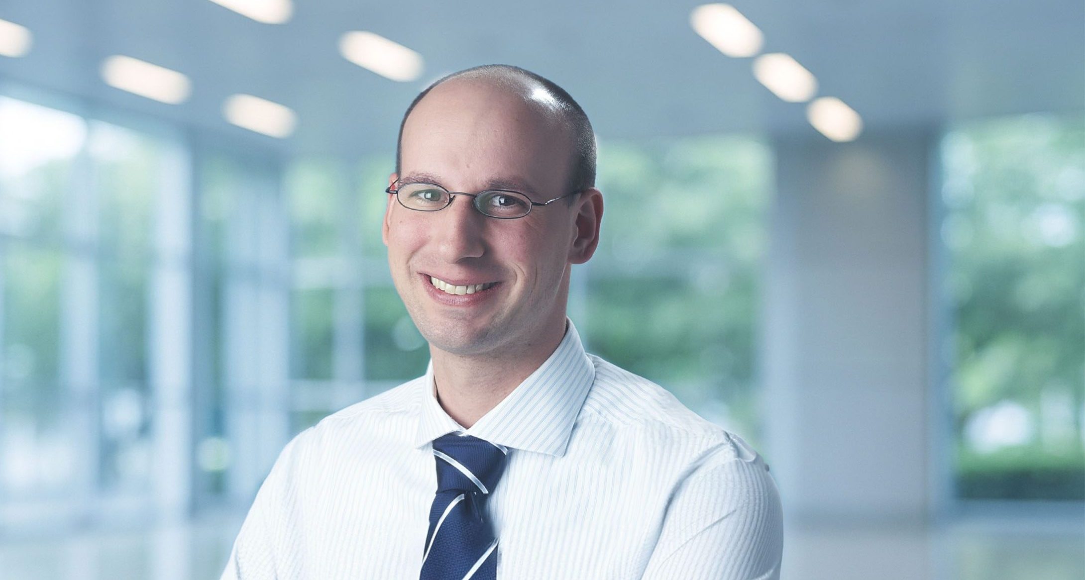 Porträt einer Person in einem modernen, lichtdurchfluteten Gebäude.