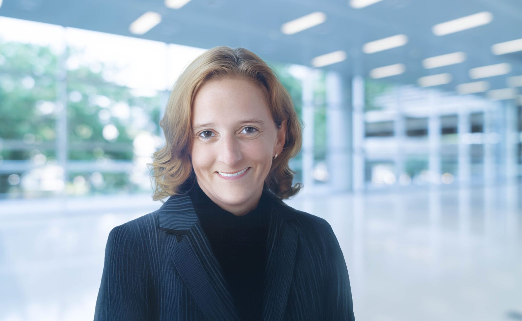 Porträt einer Person in einem modernen, lichtdurchfluteten Gebäude.