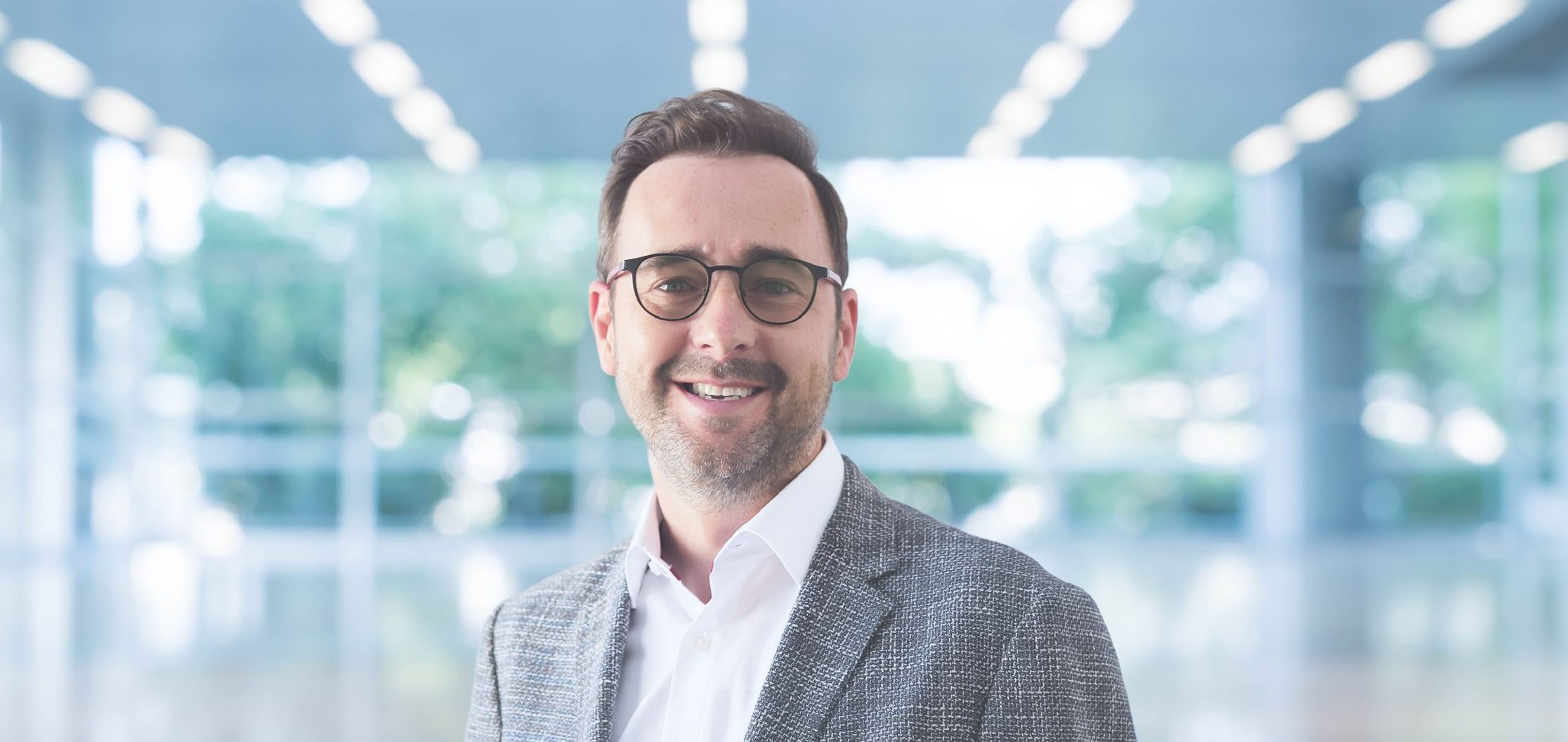 Porträt einer Person in einem modernen, lichtdurchfluteten Gebäude.