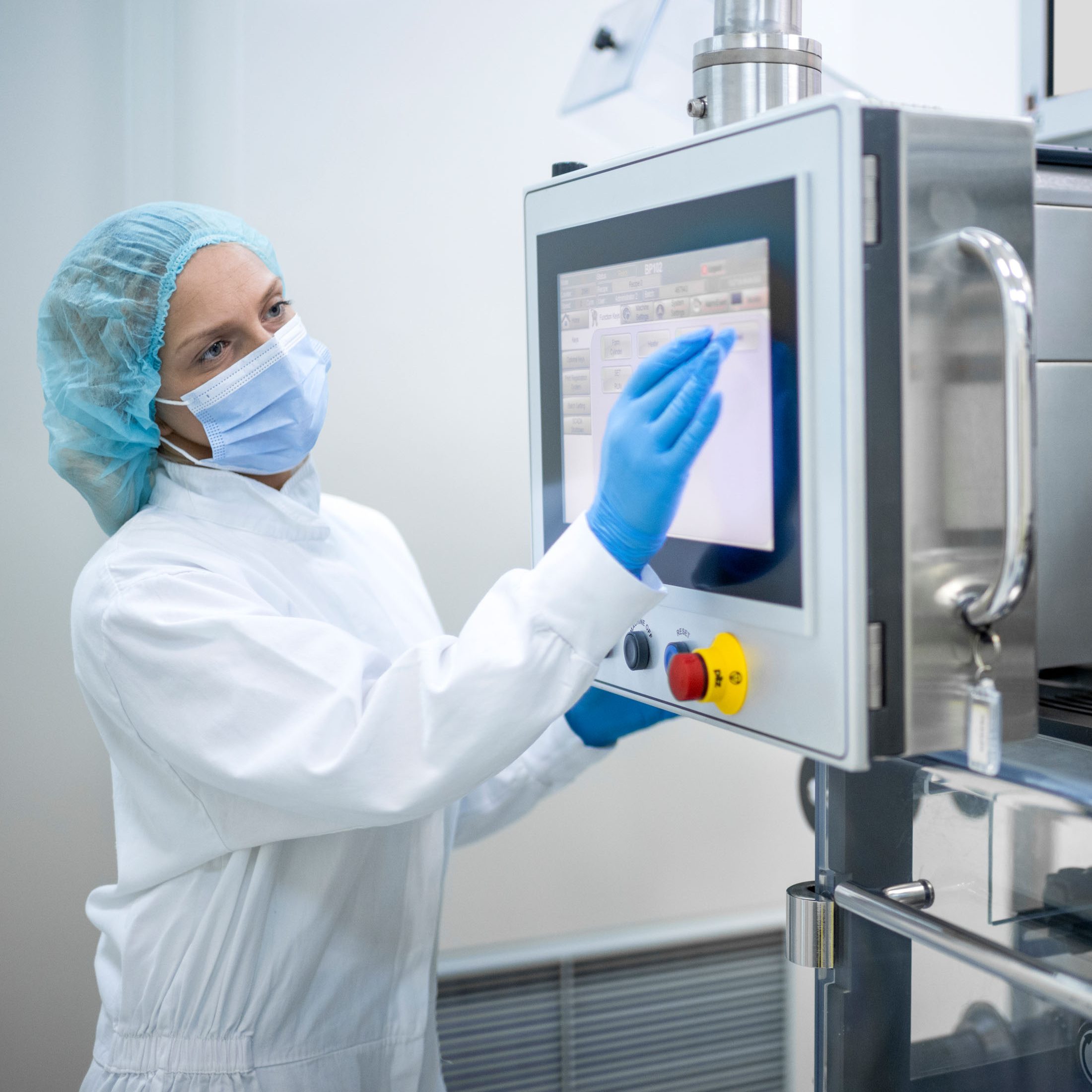 Technical specialist operates an HMI panel at a pharmaceutical plant.