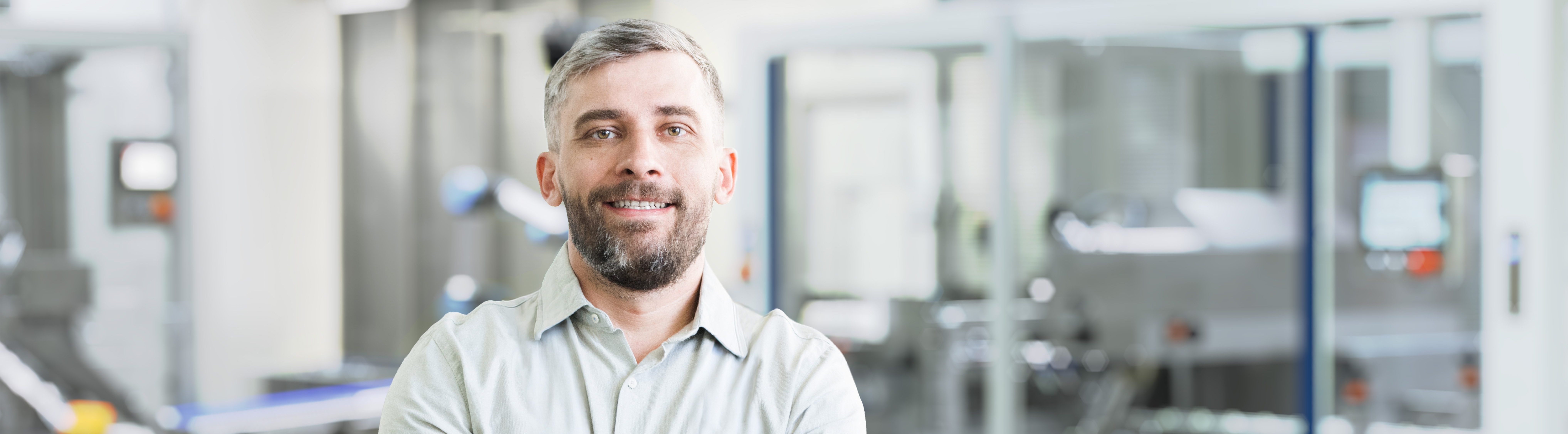 Person steht mit verschränkten Armen in einer Produktionshalle.