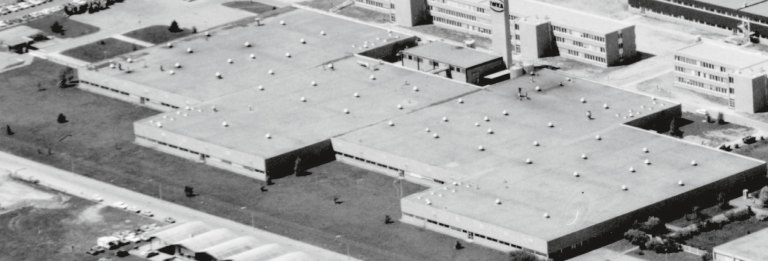 Black and white aerial view of a large factory site with hall complexes.