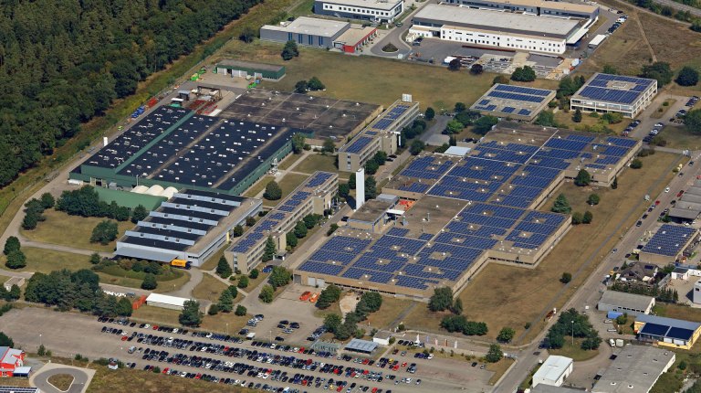 Aerial view of a modern industrial area with large-scale photovoltaic systems on the hall roofs.